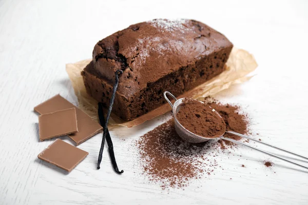 Chocolate cake dengan bubuk kakao, vanilla pod di atas meja putih — Stok Foto