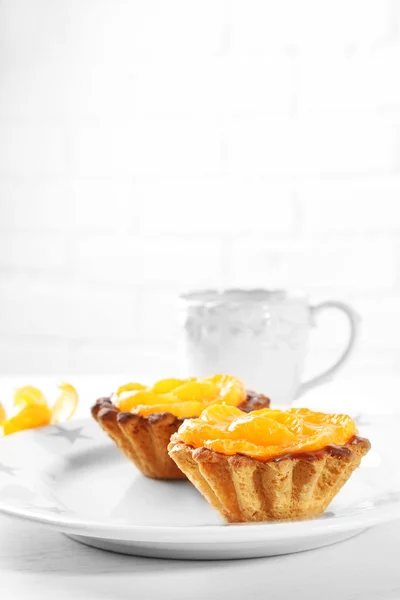 Sweet cakes with tangerines on table, close up — Stock Photo, Image