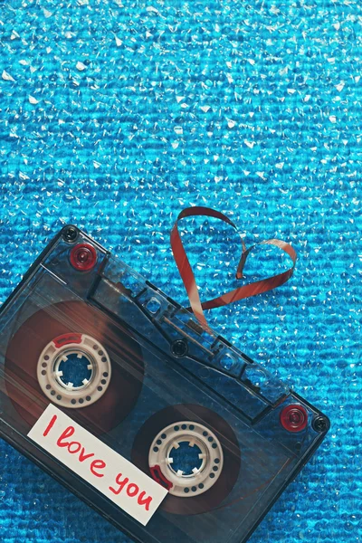 Casete de audio retro con cinta en forma de corazón sobre fondo texturizado azul — Foto de Stock