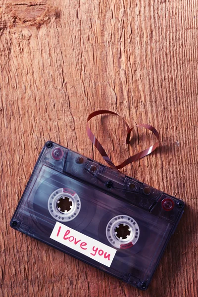 Cassetta audio retrò con nastro a forma di cuore su sfondo di legno — Foto Stock