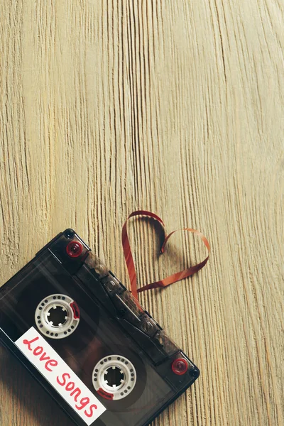 Cassete de áudio retrô com fita em forma de coração em fundo de madeira — Fotografia de Stock