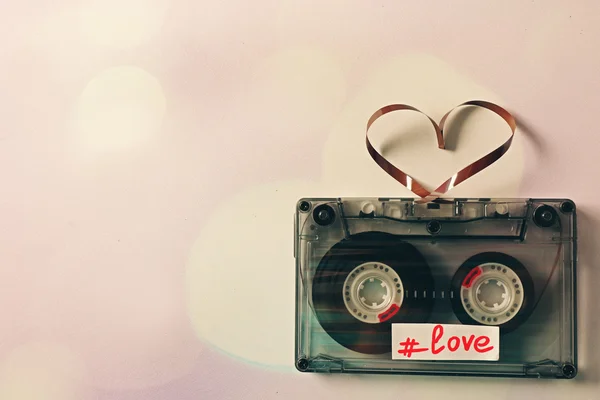 Retro audio cassette with tape in shape of heart on white background — Stock Photo, Image