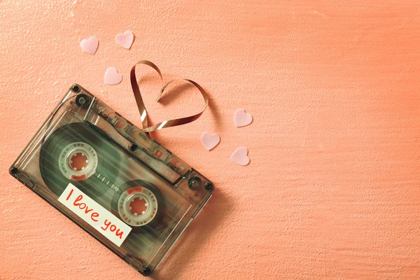 Retro audio cassette with tape in shape of heart on pink textured background — Stock Photo, Image