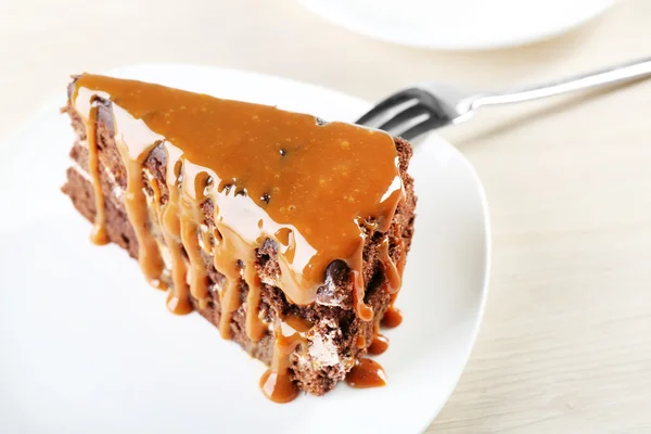 Piece of chocolate cake with caramel in white saucer close up — Stock Photo, Image