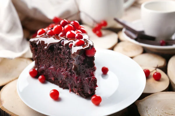Piece of chocolate cake with cranberries on wooden background, closeup — Stock Photo, Image