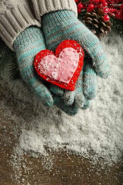 Mani femminili in guanti blu con cuore decorativo su sfondo neve — Foto Stock