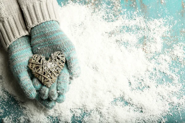 Mãos femininas em mitenes com coração no fundo da neve — Fotografia de Stock