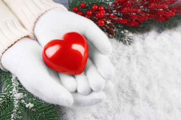 Mani femminili in guanti con cuore decorativo su sfondo neve — Foto Stock