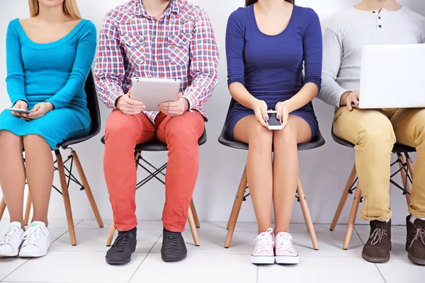 Junge Leute Mit Geräten Sitzen Auf Stühlen Weißen Saal Großaufnahme — Stockfoto