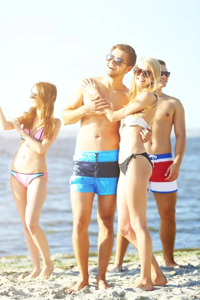 Happy couple and friends relaxing at beach — Stock Photo, Image