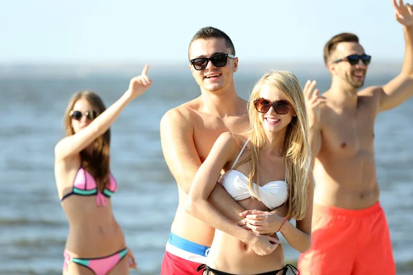 Happy couple and friends relaxing at beach — Stock Photo, Image