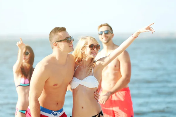 Gelukkige paar en vrienden ontspannen op het strand — Stockfoto