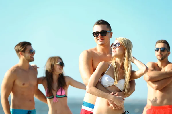 Gelukkige paar en vrienden ontspannen op het strand — Stockfoto