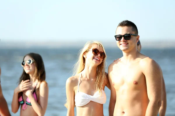 Pareja feliz y amigos relajándose en la playa — Foto de Stock