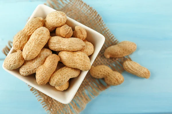 Peanuts in the bowl on blue — Stock Photo, Image