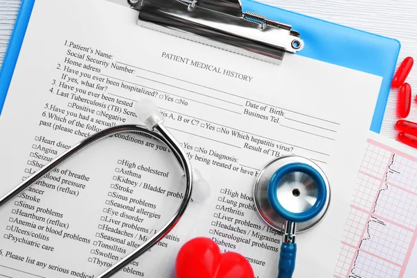 Stethoscope, pills, plastic heart on table — Stock Photo, Image