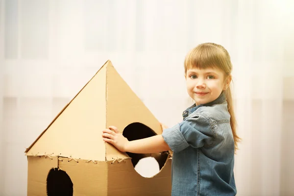 Girl playing with cardboard space rocket — Stock Photo, Image