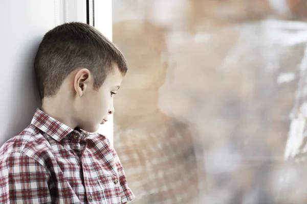 Sad boy sitting near window — Stock Photo, Image