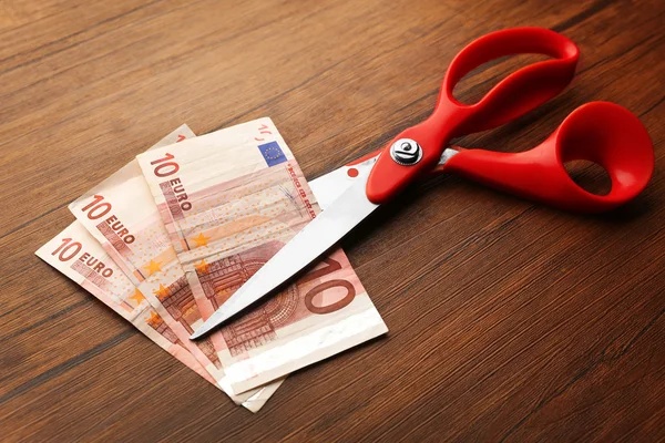 Red scissors cut money