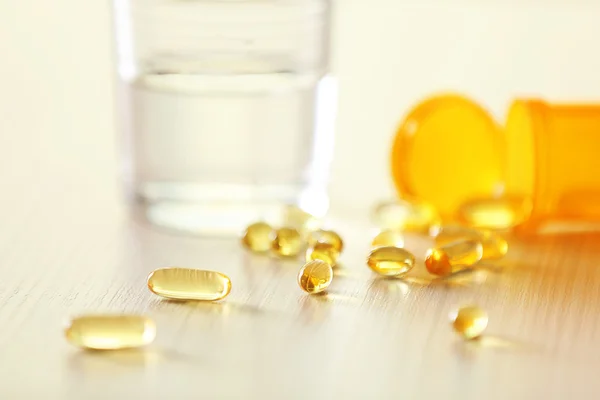 Yellow capsules spilled from pill bottle — Stock Photo, Image