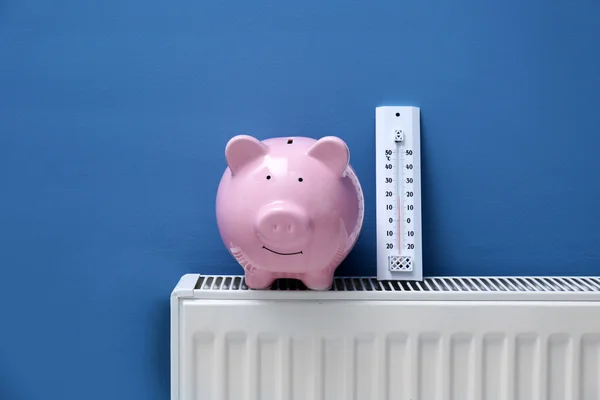 Piggy bank on radiator — Stock Photo, Image