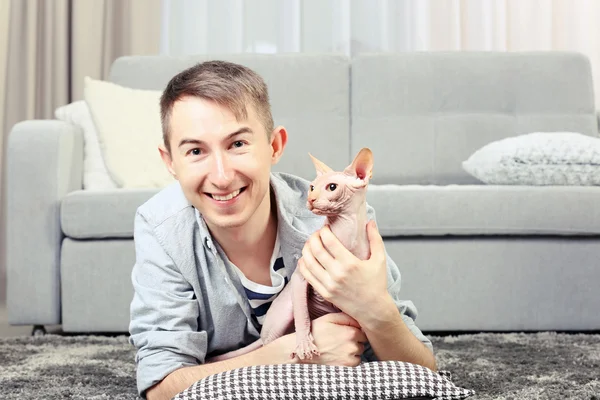 Hombre guapo se acuesta con gato en el suelo — Foto de Stock