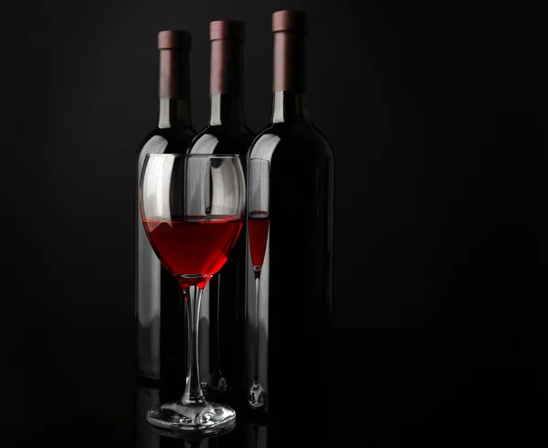 Bicchiere di vino rosso contro le bottiglie — Foto Stock