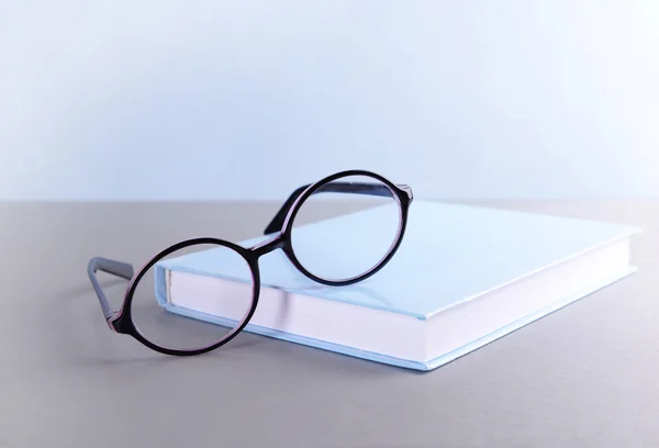 Boek en brillen op grijze tafel — Stockfoto