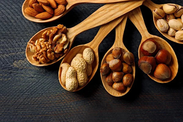 Lepels met noten op houten achtergrond — Stockfoto