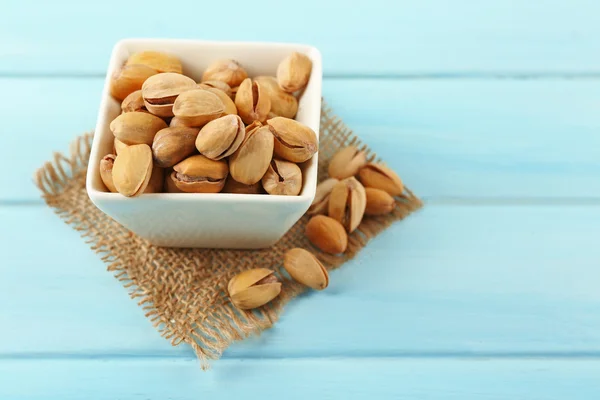 Pistachios in the bowl on blue — Stock Photo, Image