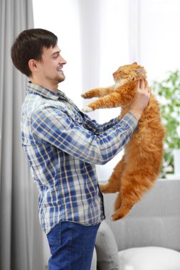 Kırmızı kedi ile genç adam ayakta