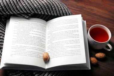 Açık kitap, fincan çay ve fındık