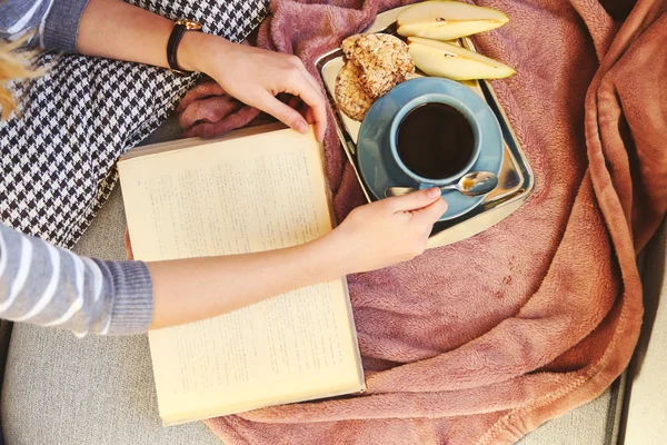 Hands with open book, plaid, fruits and coffee — Stock Photo, Image