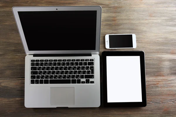 Um laptop prata aberta, telefone celular e tablet — Fotografia de Stock