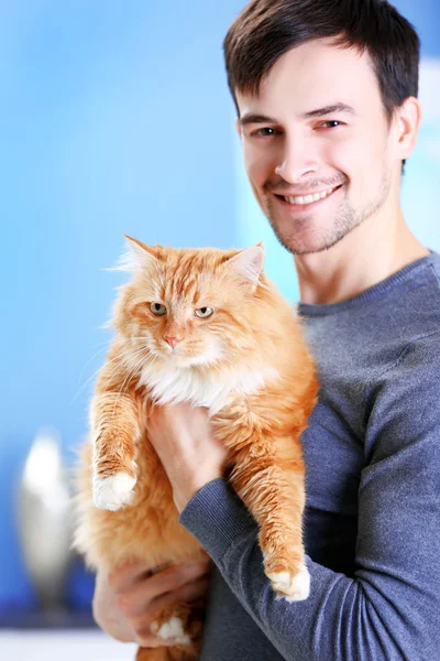 Улыбающийся молодой человек с красной кошкой — стоковое фото