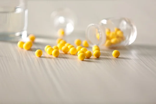 Cápsulas amarelas derramadas do frasco da pílula — Fotografia de Stock