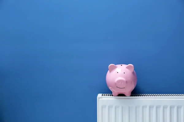 Piggy bank on radiator — Stock Photo, Image