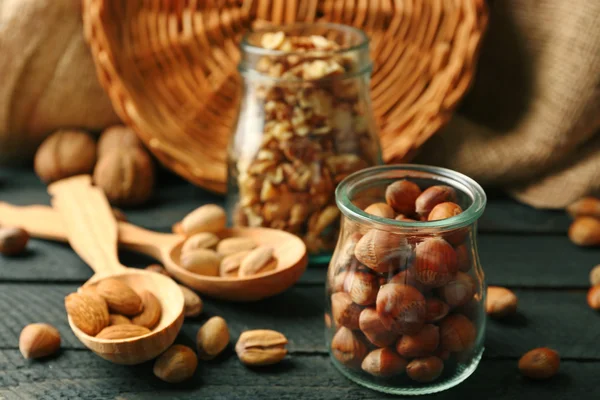 Mix van noten in de glazen potten en een houten lepel, op tafel — Stockfoto
