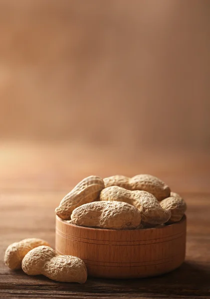 Cacahuetes en el cuenco de madera en la mesa, primer plano — Foto de Stock