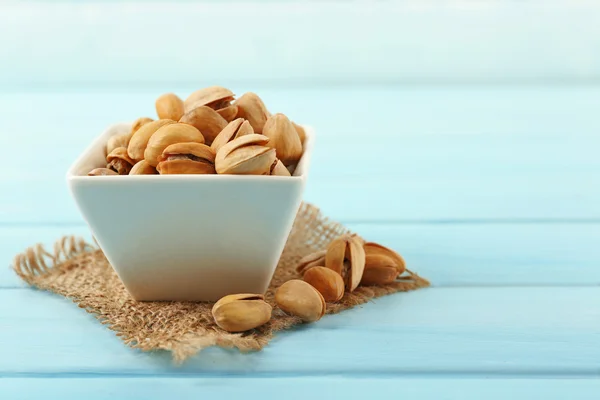 Pistacchi nella ciotola su fondo di legno blu — Foto Stock