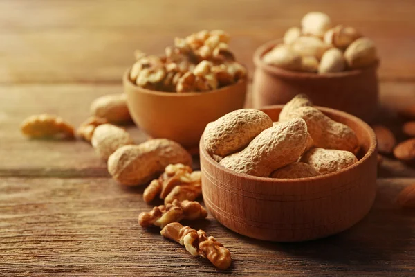 Pistácie, mandle, arašídy a vlašských ořechů v dřevěné misky na stole, detail — Stock fotografie