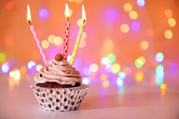 Cupcake de chocolate saboroso com creme de manteiga e velas em um fundo brilhante — Fotografia de Stock