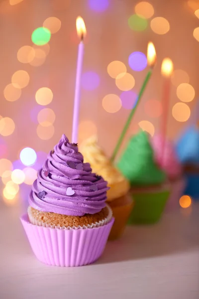 Cupcake with purple cream icing and candle — Stock Photo, Image