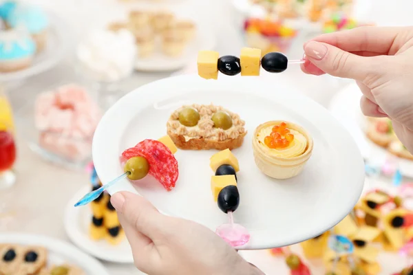 Frau hält Teller mit Snacks und Canape — Stockfoto