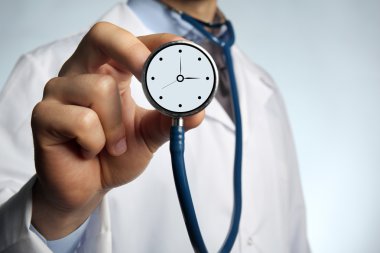 Doktor holding stetoskop ile masa saati