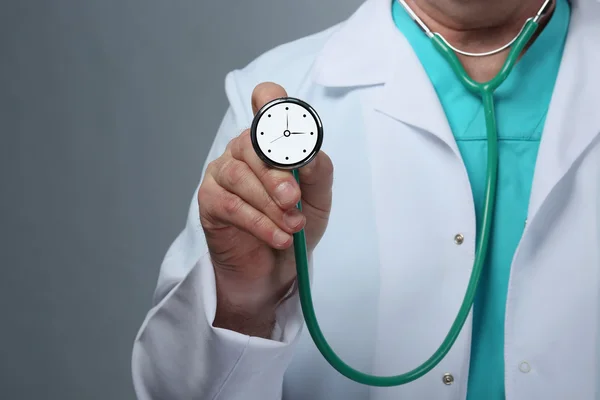 Doctor holding stethoscope with clock — Stock Photo, Image