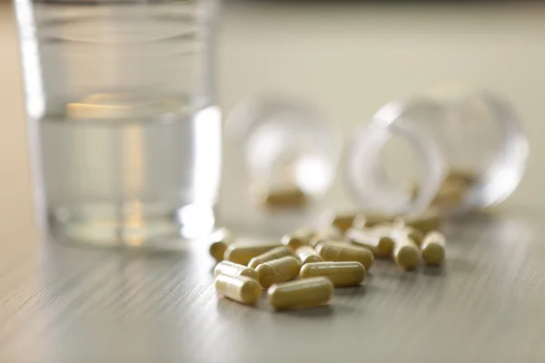 Gele capsules en glas water — Stockfoto