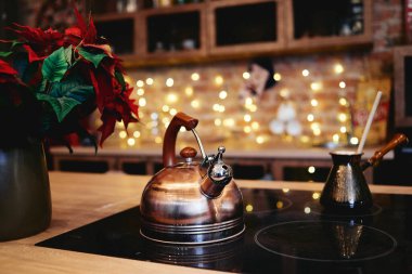 Christmas flower and metal kettle on table with bokeh lights on background, copy space. Christmas concept.  clipart