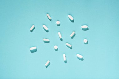 Mavi arka planda beyaz ilaç, tablet ve kapsüller, kopyalama alanı. Üst manzara, şişko. Tıp konsepti. Eczacılık.