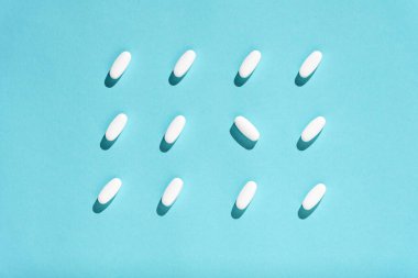 Açık mavi arka planda tıbbi haplarla moda, kopyalama alanı. Yaratıcı tıp konsepti. Asgari düzeyde. Üst manzara, düz uzanma